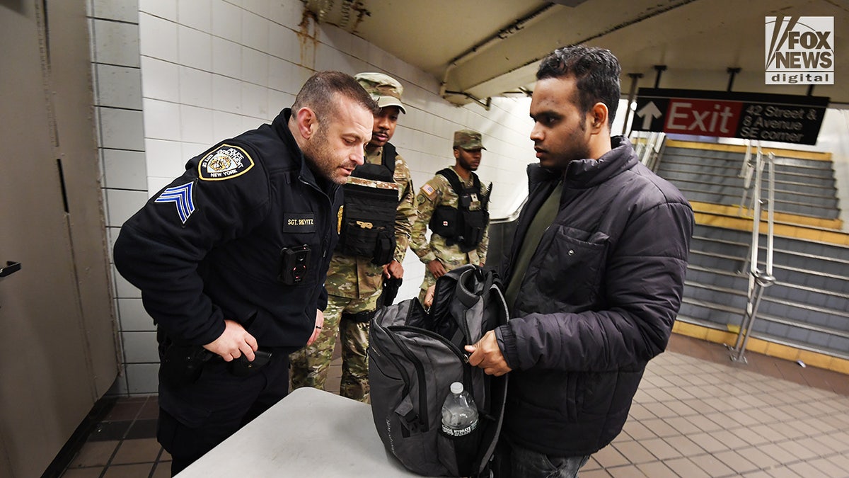 Members of the NYPD and National Guard conduct random bag searches in the New York City subway system