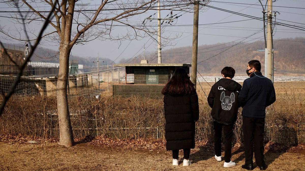 North Korean defectors stand in front of the demilitarized zone separating the two Koreas