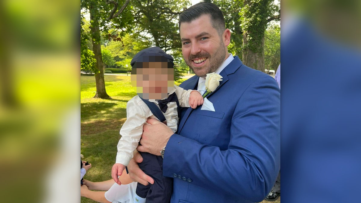 Officer Jonathan Diller holding a child and wearing a blue suit