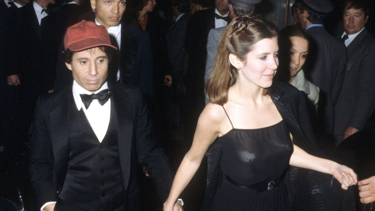Carrie Fisher walking with Paul Simon behind her