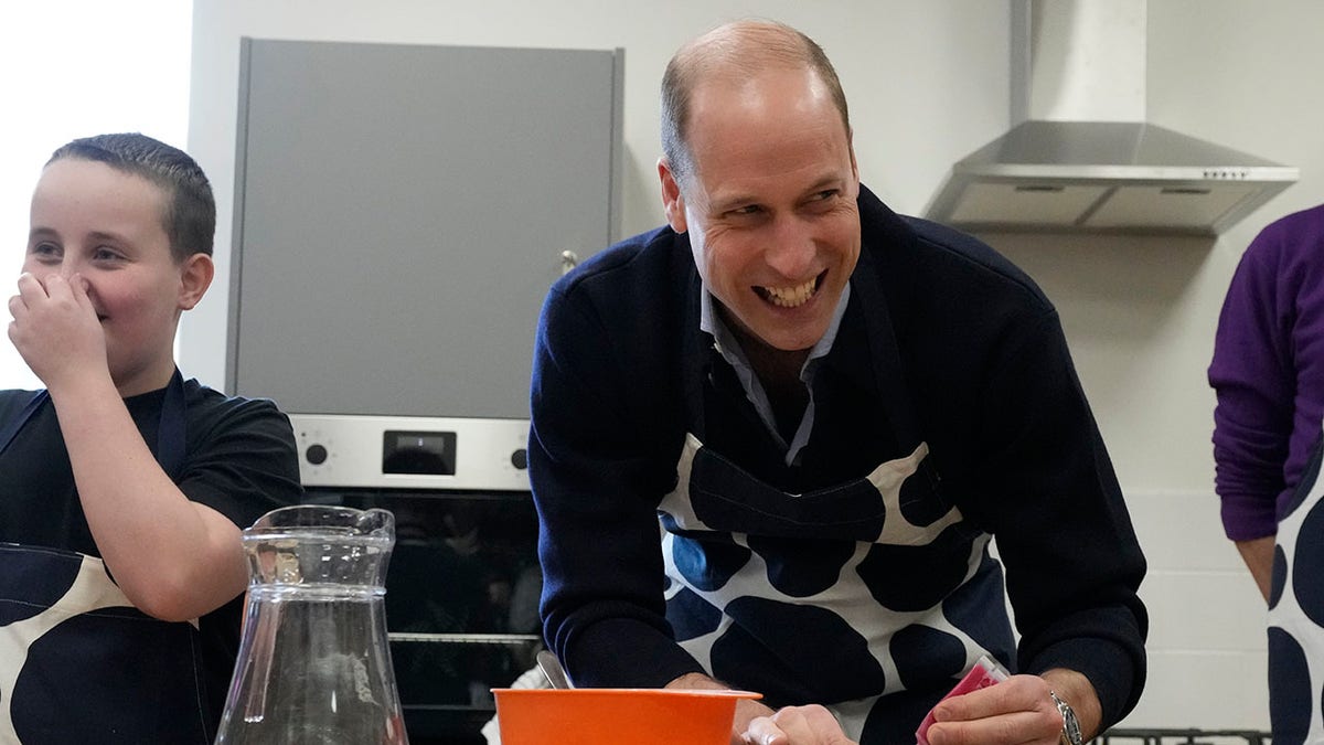 Prince William decorating a cookie with a child at a charity event
