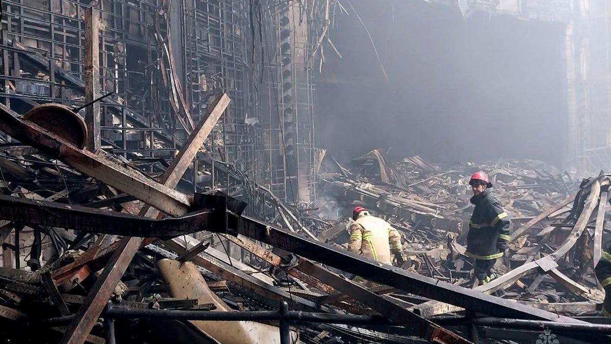 Russian firefighters work in the burned concert hall after an attack