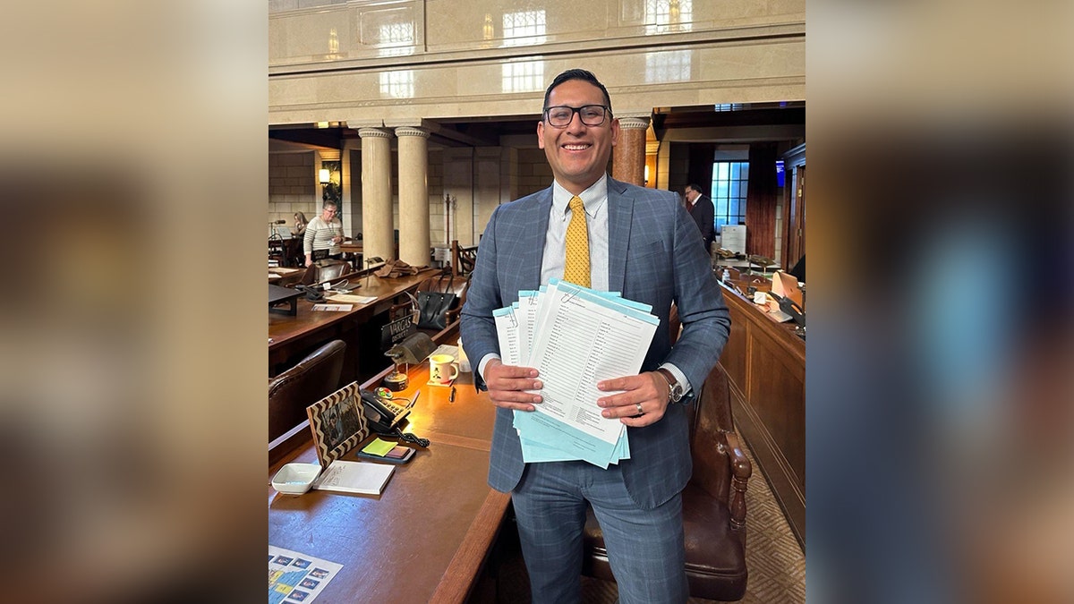 Senator Tony Vargas holding pieces of legislation