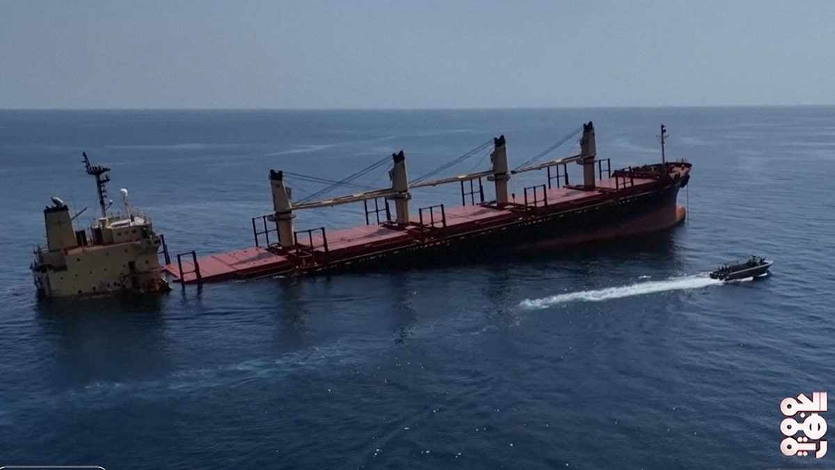 Side view of a cargo ship in the ocean that was struck by Iran-backed Houthi rebels is sinking, next to a smaller boat