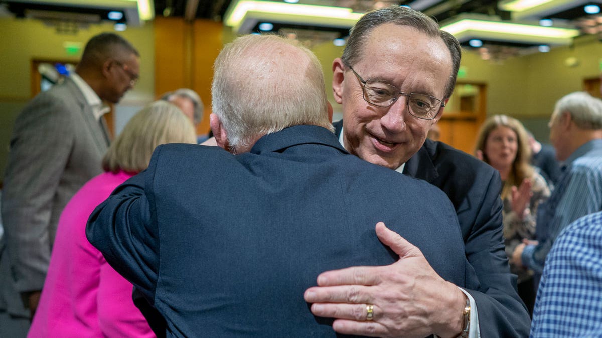 Jeff Iorg hugs presidential search team chair Neal Hughes