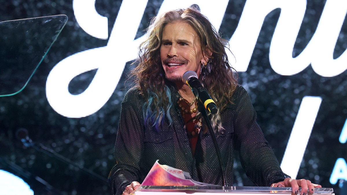 Steven Tyler smiling at a podium