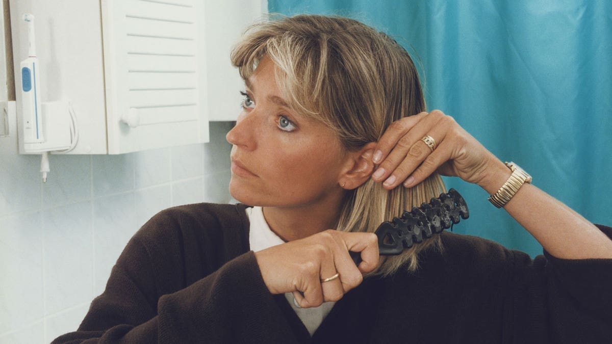 Uma mulher escova o cabelo com uma escova ventilada