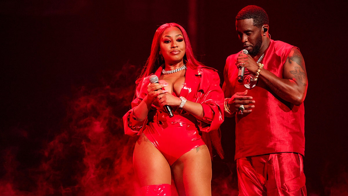 Yung Miami and Sean "Diddy" Combs both wearing red and performing on stage together