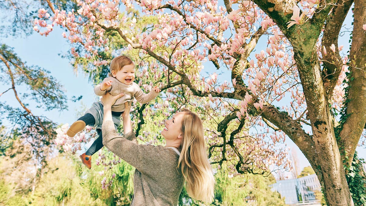 mother with young child under magnolia tree