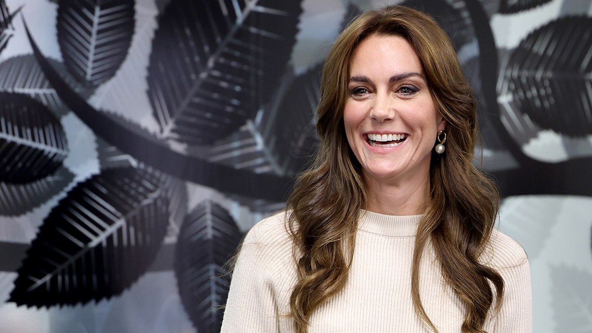 Kate Middleton in a cream sweater smiles