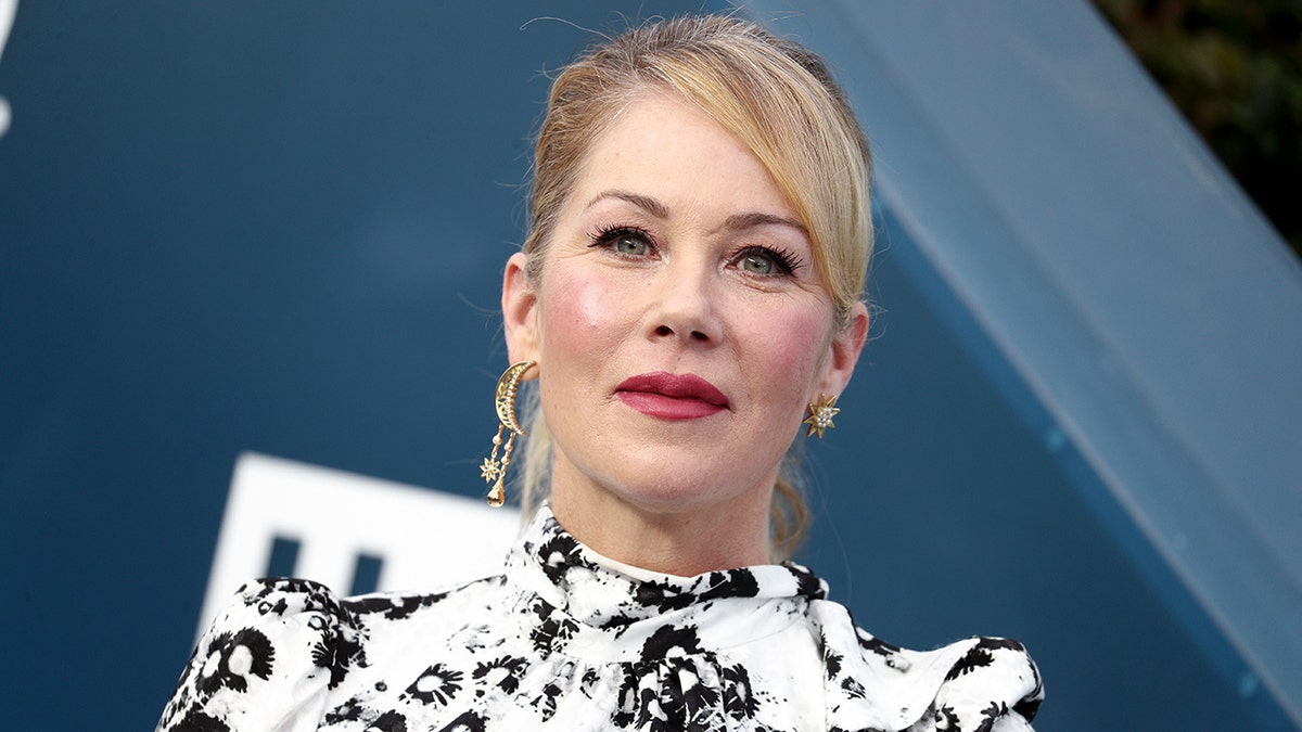 Christina Applegate looks up in a white and black patterned dress