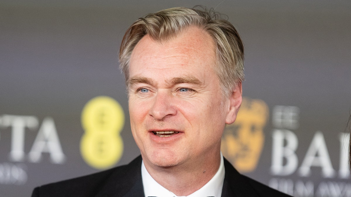 Christopher Nolan looks off on the carpet at the BAFTAS in a black suit