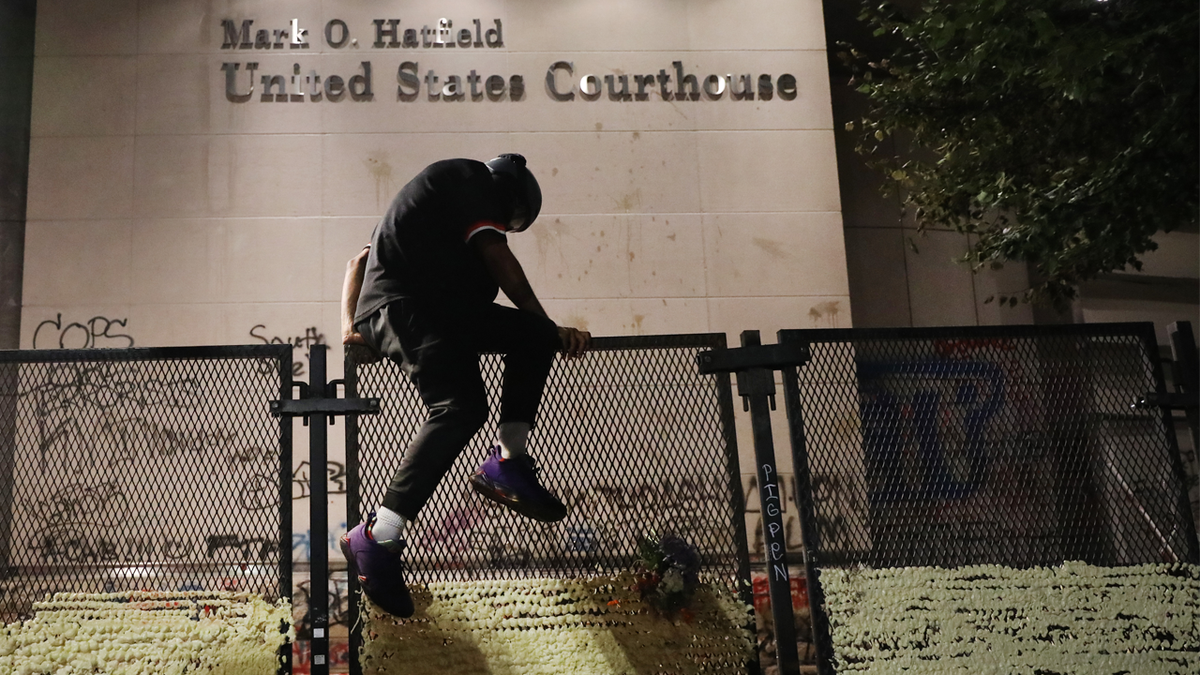 Protester climbs over fence blocking Portland courthouse