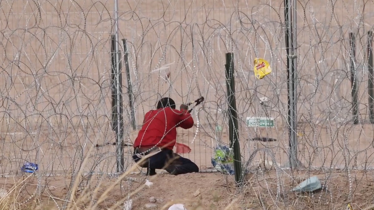 Migrant cutting border fence