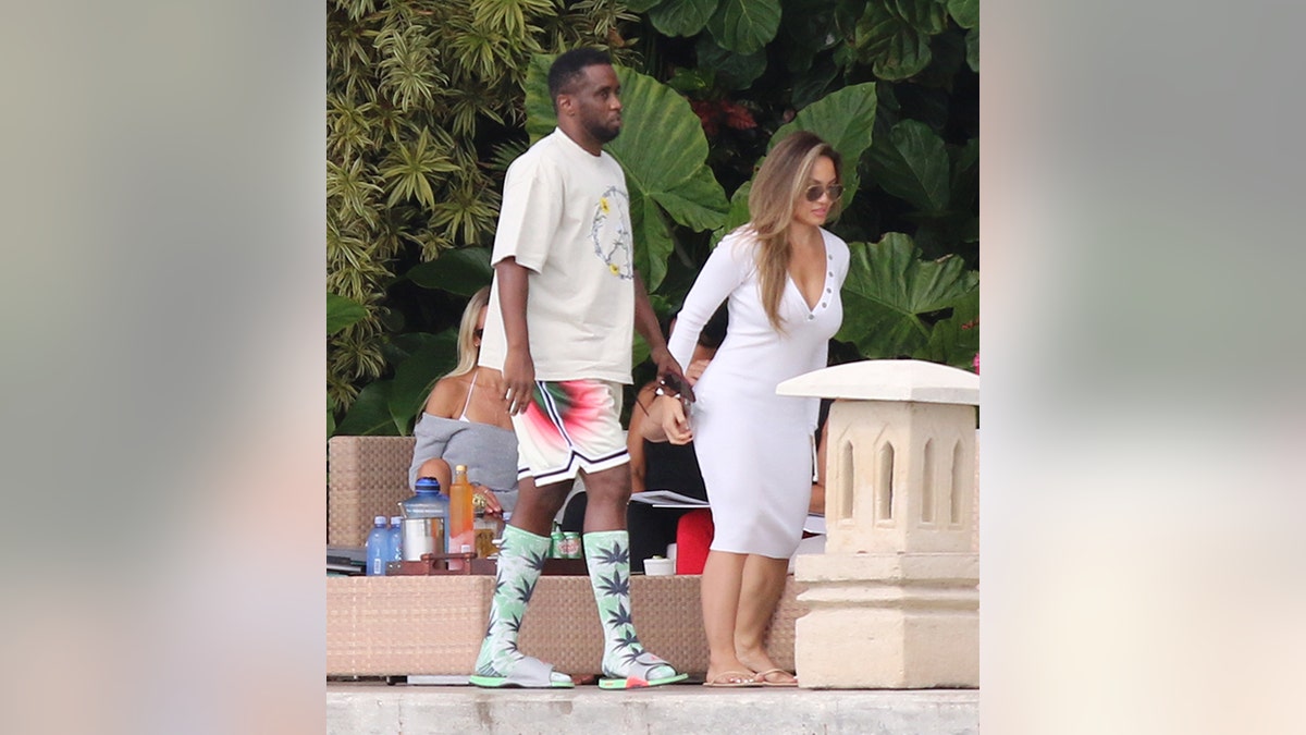 Diddy con camisa blanca y pantalones cortos blancos, rojos y verdes pasea junto a Daphne Joy con un vestido blanco en Miami Beach