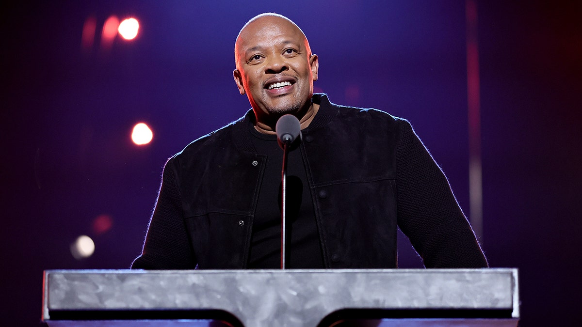 Dr. Dre olha para trás de um pódio de pedra na cerimônia de posse do Rock & Roll Hall of Fame