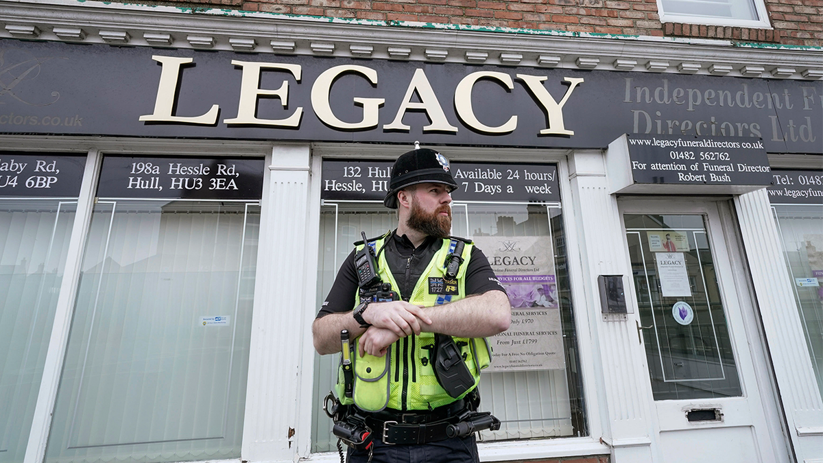 Police stand guard outside the Beckside branch of Legacy Independent Funeral Directors