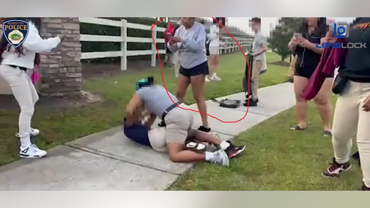 Taitayana Duffy (circled) appears to be recording the fight and allegedly cheering the student