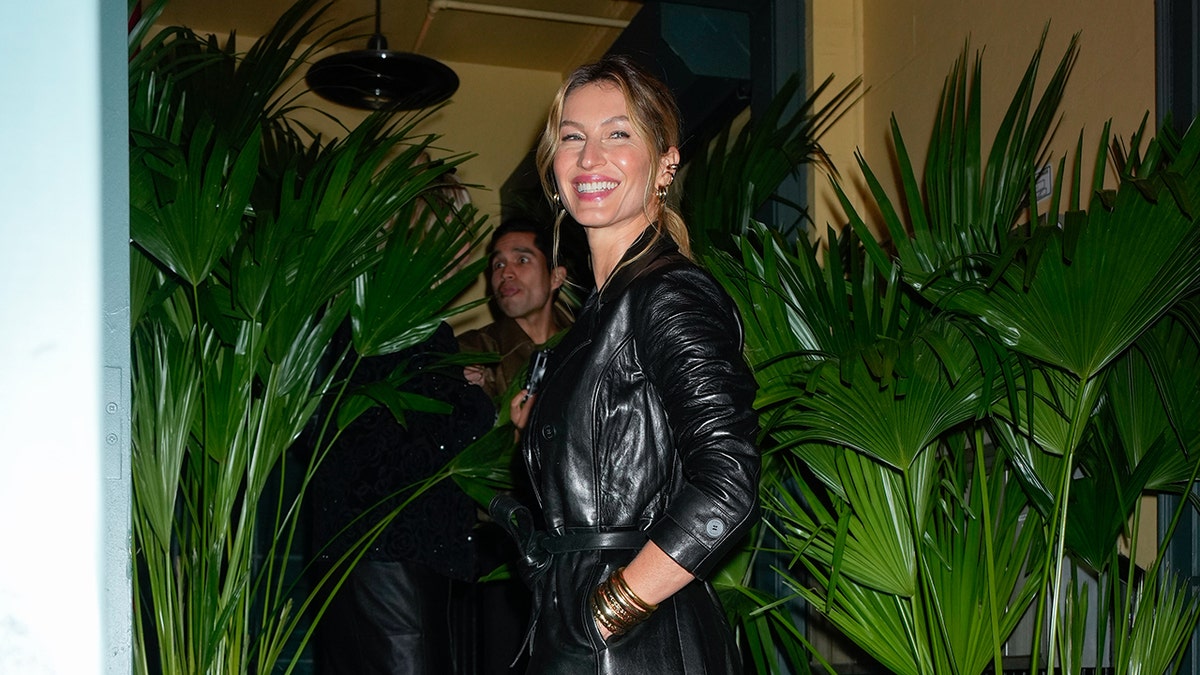 Gisele Bündchen in a black leather jacket turns around and smiles for fans in New York