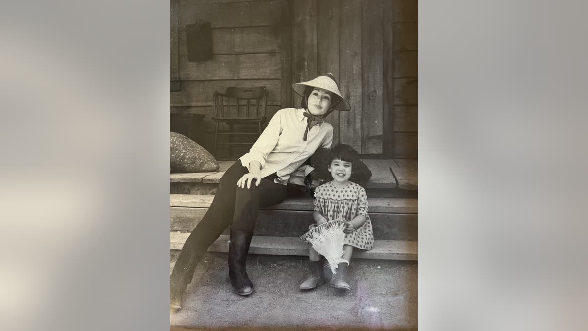 Uma foto antiga de Barbara Rush e sua filha sentadas em uma escada.