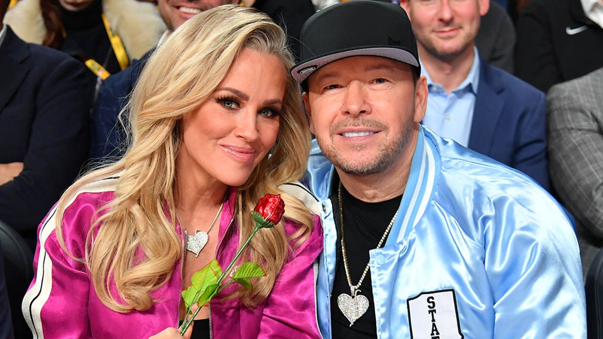 jenny mccarthy holding rose and smiling with donnie wahlberg
