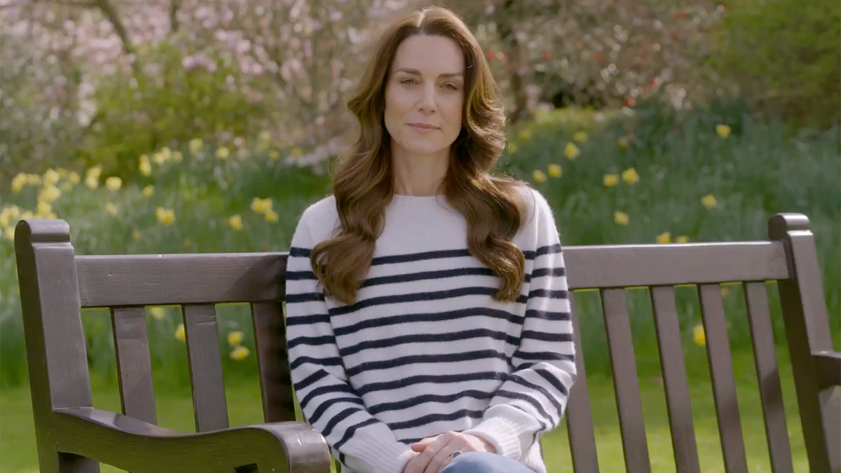 Kate Middleton in a white top with navy blue stripes sits on a bench to announce that she has cancer