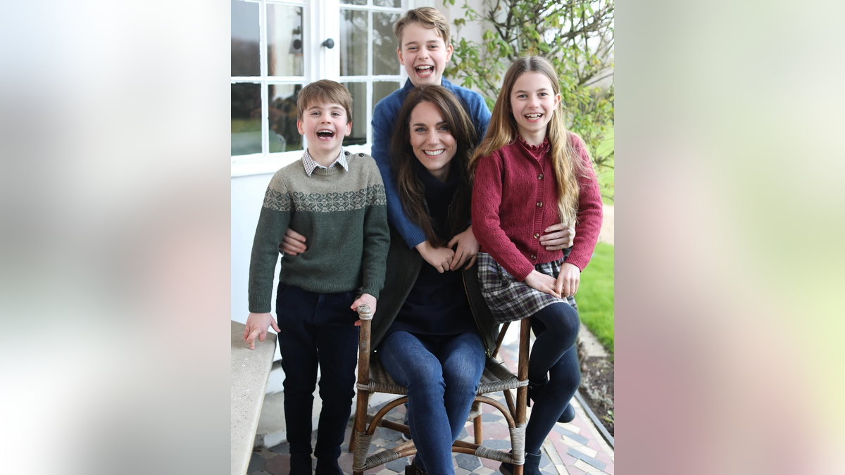 Kate Middleton sits in a chair and is hugged by her eldest son Prince George and stands next to her kids Prince Louis and Princess Catherine