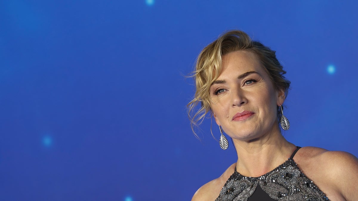 Winslet soft smiles in a black dress on the carpet for "Avatar" with a curly updo