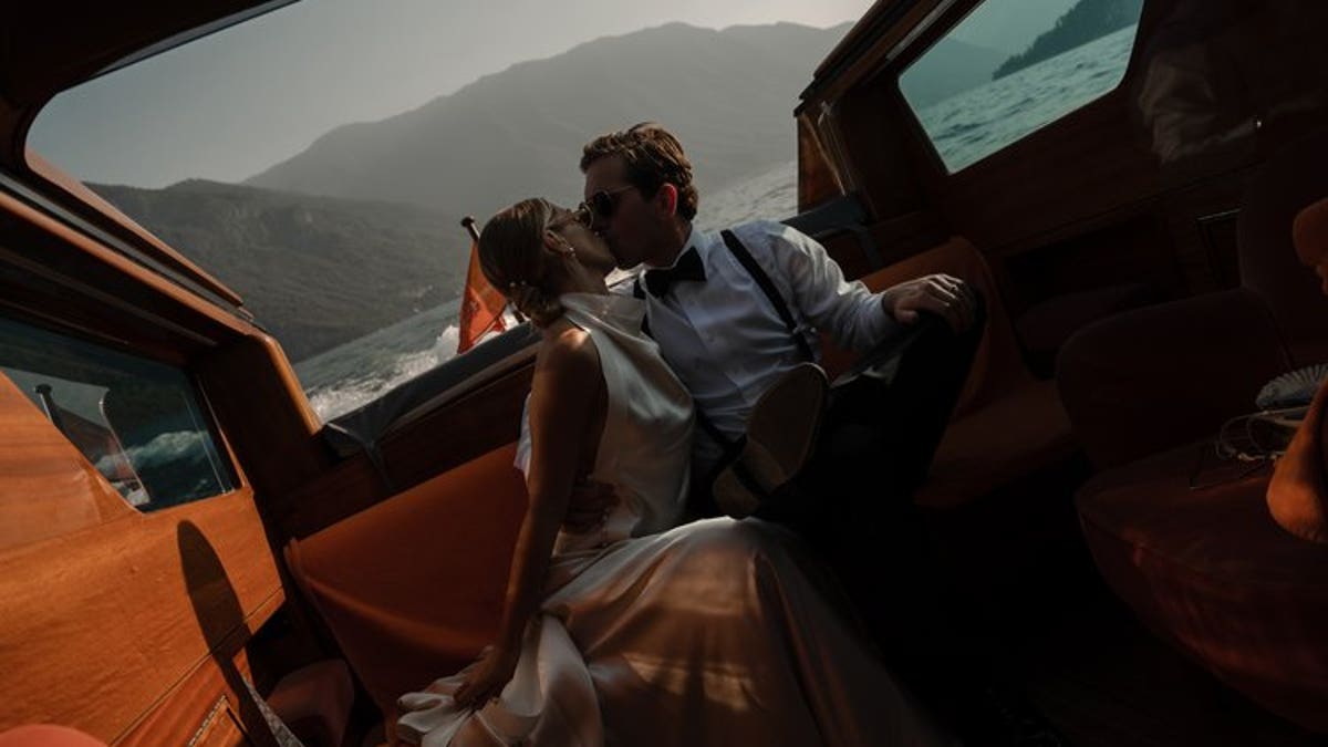 A bride and groom kiss while on a boat