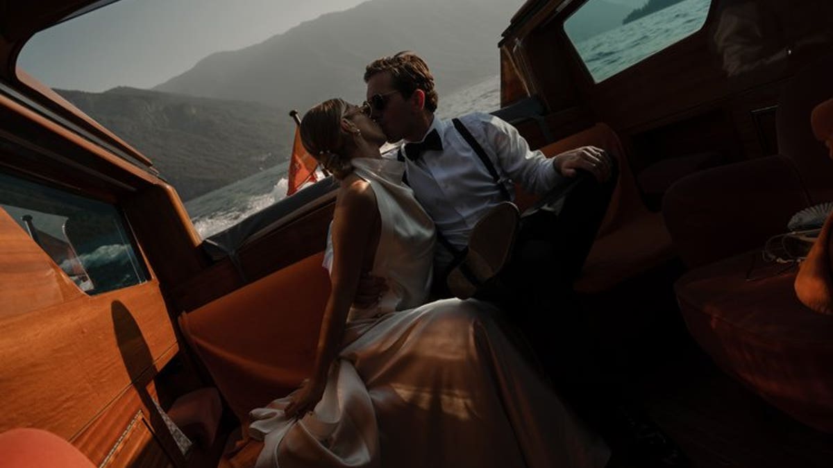 A bride and groom kiss while on a boat