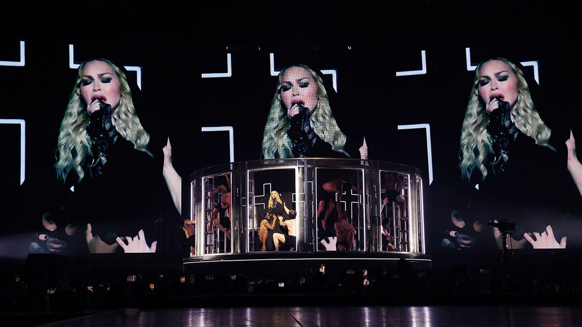 Madonna sings on stage with her face projected above her