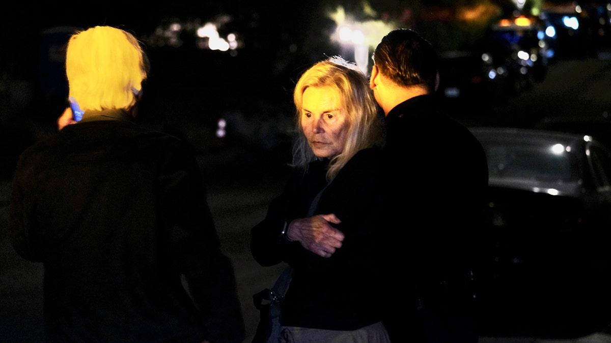 Grief-stricken Suzanne Perry is hugged outside the home of her son, Matthew Perry