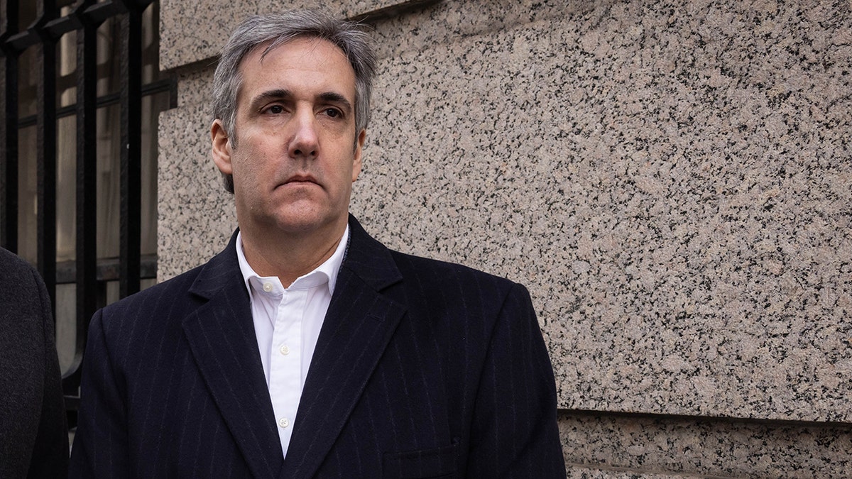 Michael Cohen in black coat, white shirt, frowning
