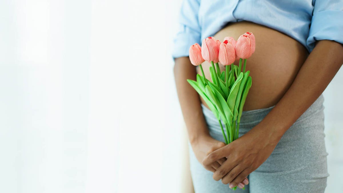 pregnant female holding flowers