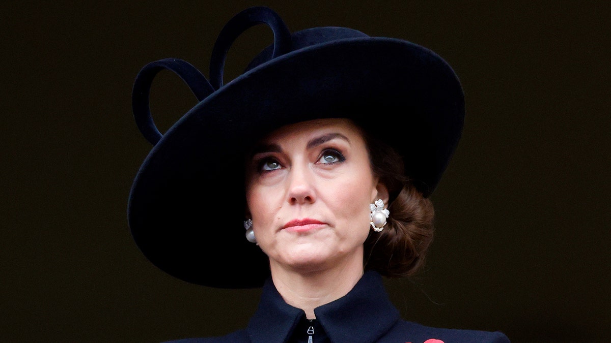 Kate Middleton parece solene em uma roupa preta e chapéu enquanto olha para cima