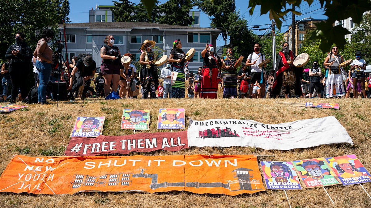 Indigenous protesters drum by signs calling to shut down youth prisons