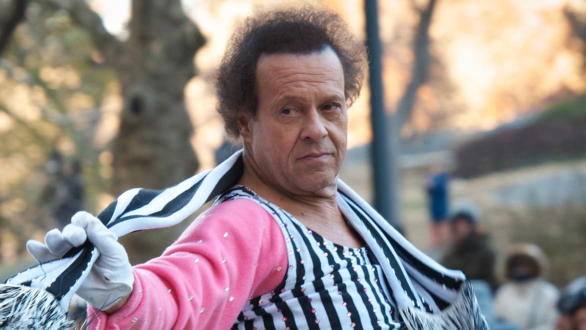 Richard Simmons in a pink sweater overlayed with a black and white striped piece is pictured out in New York