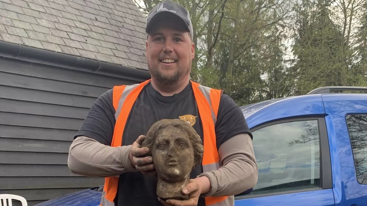 Digger Greg Crawley holds the head of a Roman sculpture that he unearthed during a construction project.