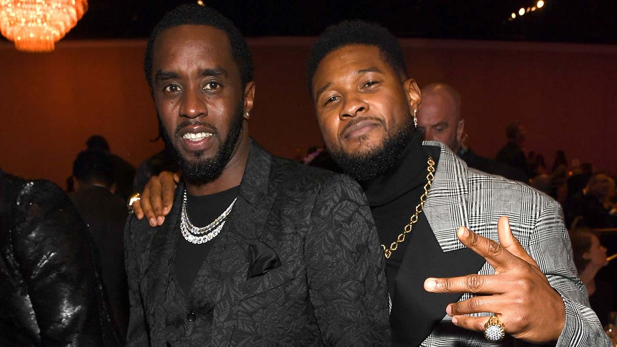 Sean Combs smiles wearing black suit with Usher in grey plaid jacket