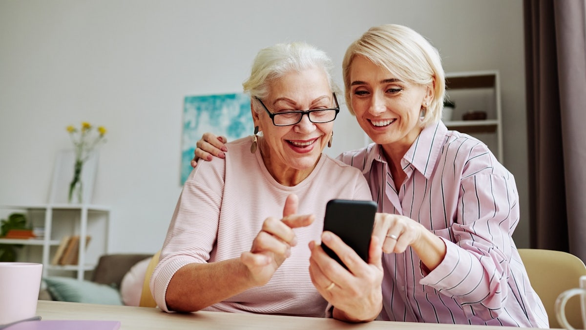 senior looking at smartphone with family member