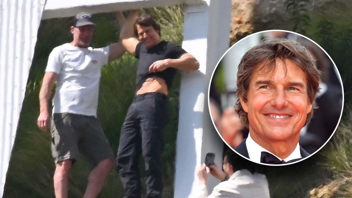 Actor Tom Cruise sports black T-shirt with slacks while hanging on to Hollywood sign