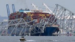 A boat moves past a container ship as it rests against wreckage of the Francis Scott Key Bridge on Tuesday, March 26, 2024, as seen from Pasadena, Md. The container ship lost power and rammed into the major bridge in Baltimore early Tuesday, causing it to snap and plunge into the river below. Several vehicles fell into the chilly waters, and rescuers searched for survivors.