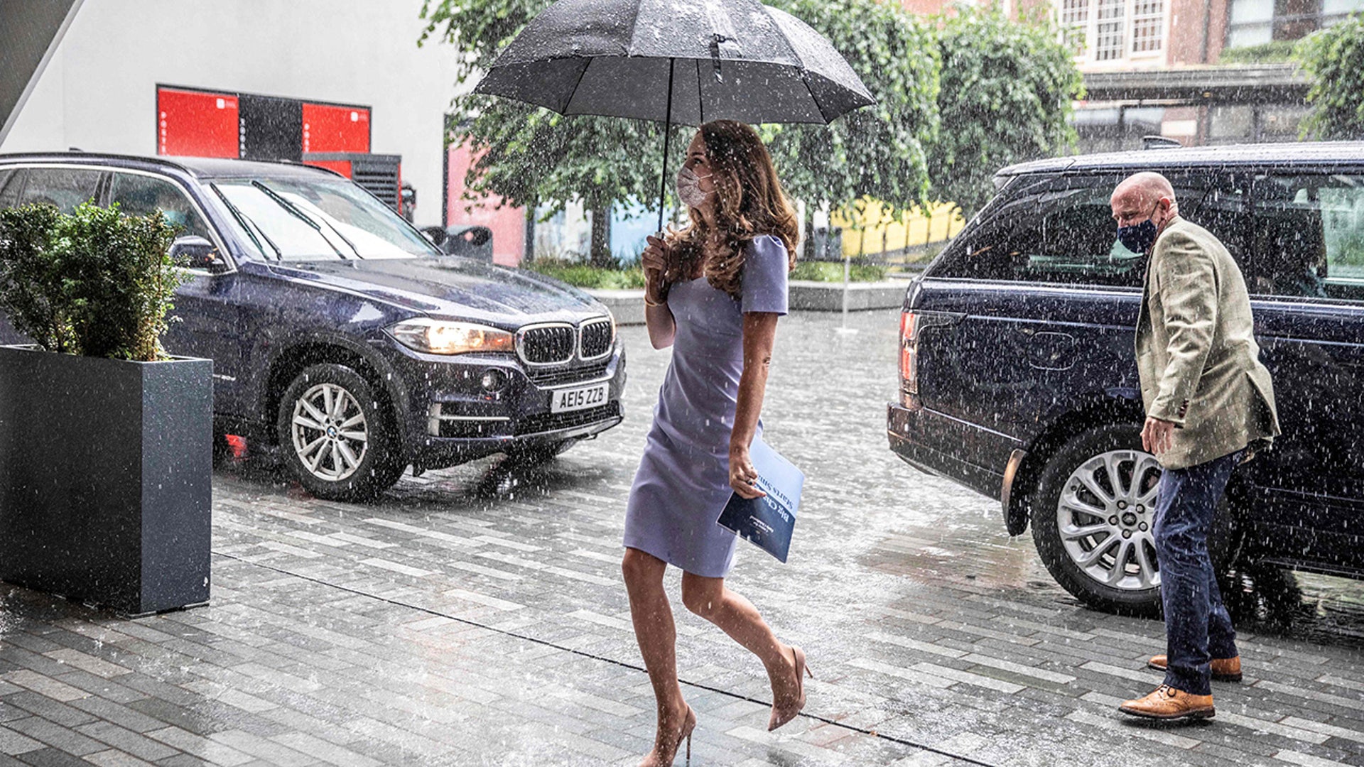 Princess Catherine under an umbrella while wearing a covid mask
