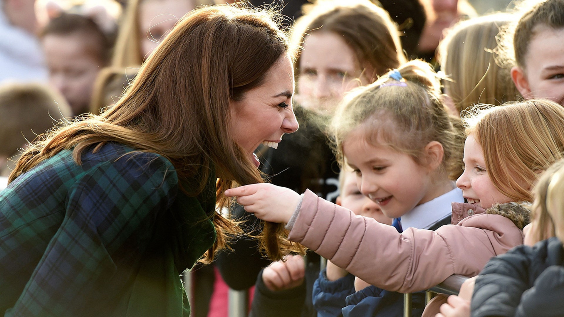 A young girl touches Princess Catherine's hair