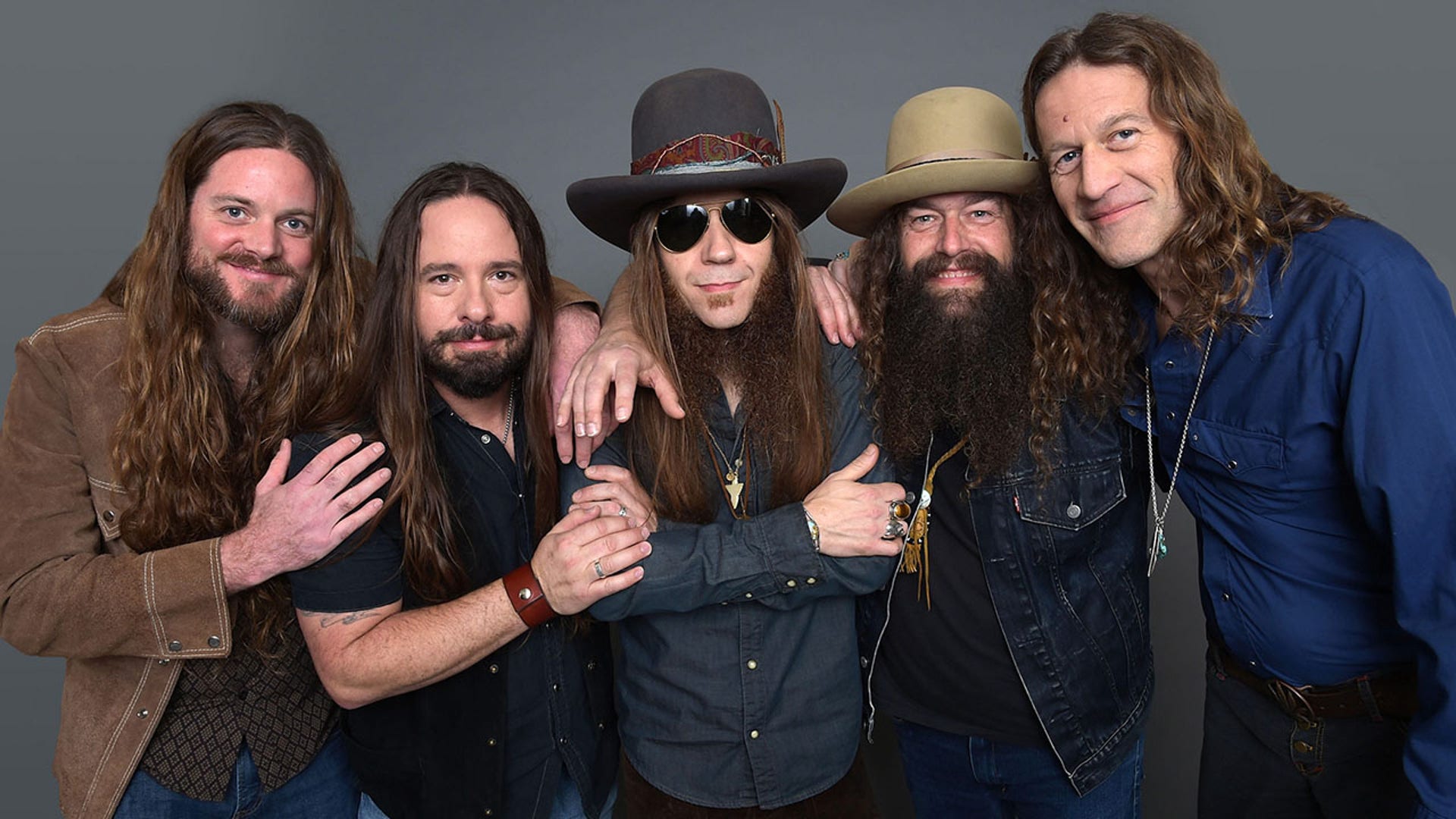 Brandon Still in a brown jacket stands next to Paul Jackson in a navy shirt and black vest, next to Charlie Starr with sunglasses and a big hat and Brit Turner with a big hat, and Richard Turner in a blue shirt