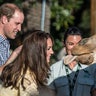 A giraffe sticks out its tongue at Kate Middleton while Prince William looks on