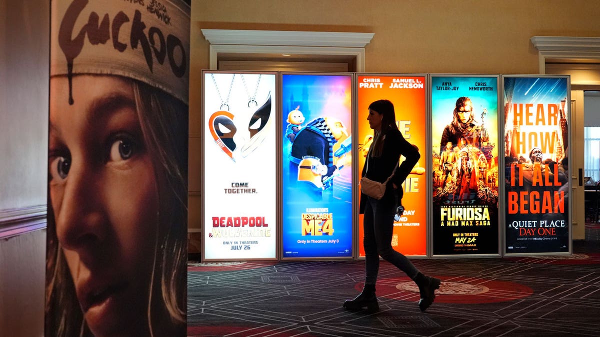 A visitor walks past advertisements for upcoming movies