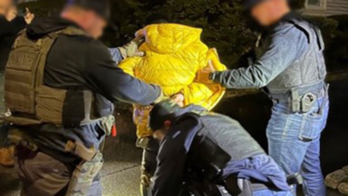 Police arresting Colombian national wearing a yellow jacket
