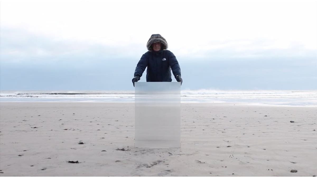 Man behind the invisibility shield on a beach 