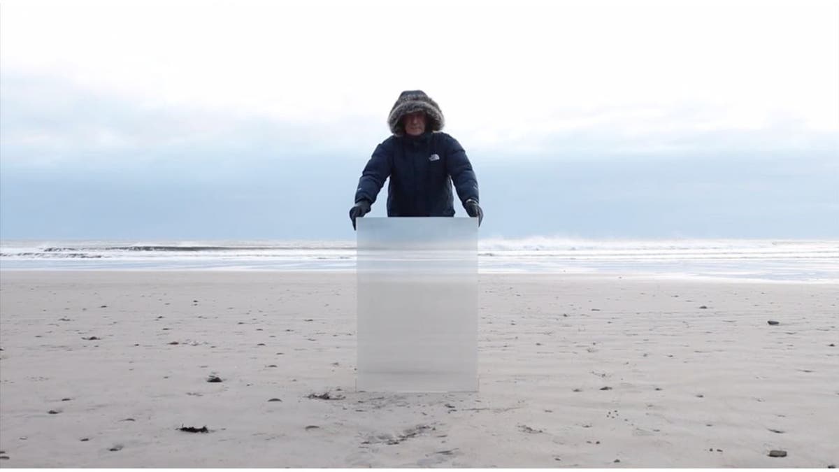 Ein Mann hinter einem verschwindenden Schild am Strand 